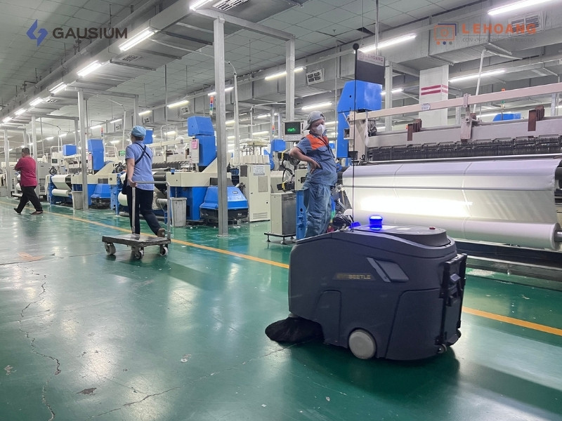 Robot Gausium Beetle tự động lau sàn giữa các dây chuyền sản xuất dệt may với công nhân đang làm việc