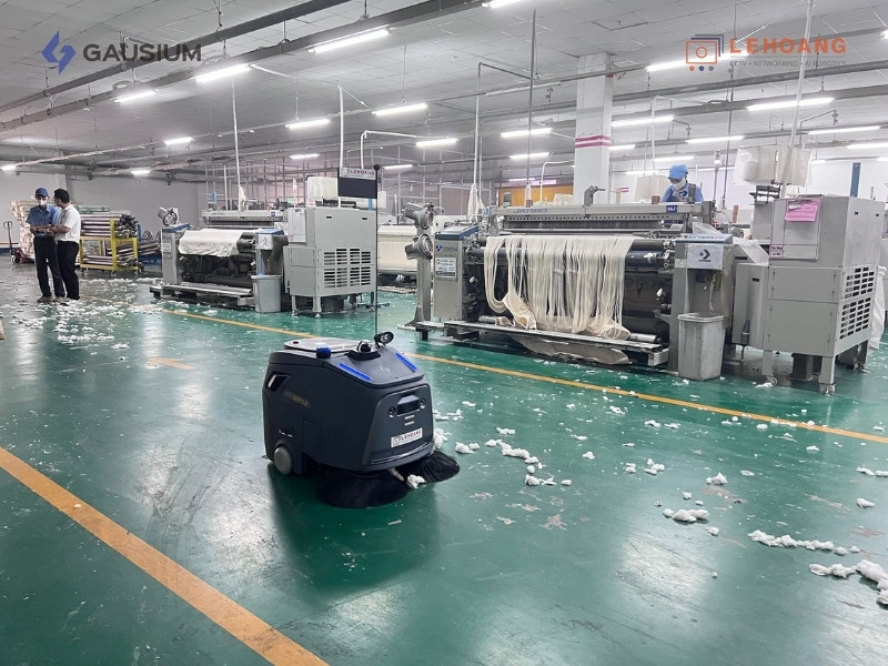 Robot vệ sinh Beetle vận hành tự động trong khu vực sản xuất dệt may với nhiều rác thải vải