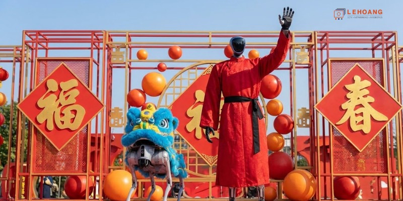 Robot hình người Unitree mặc trang phục truyền thống đỏ biểu diễn cùng robot chó đội đầu lân tại Xuân Vãn 2026 – Lê Hoàng Robotics nhà phân phối chính hãng Unitree tại Việt Nam