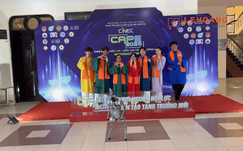 Sinh viên và đại biểu CAPE 2026 chụp hình kỷ niệm cùng robot Unitree Go2 Pro trước backdrop sự kiện
